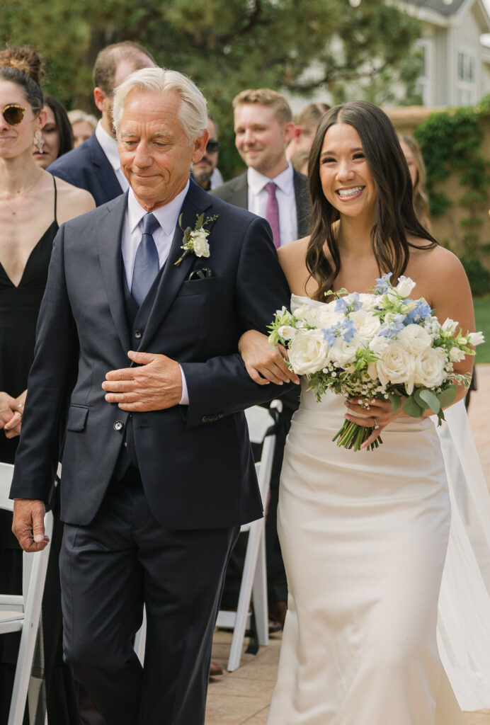 Bride walking down the aisle with her father during the outdoor ceremony at Villa Parker in Colorado.