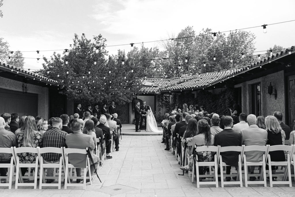 Wide shot of the ceremony at Villa Parker showing guests, the courtyard, and European architecture during a Colorado wedding.