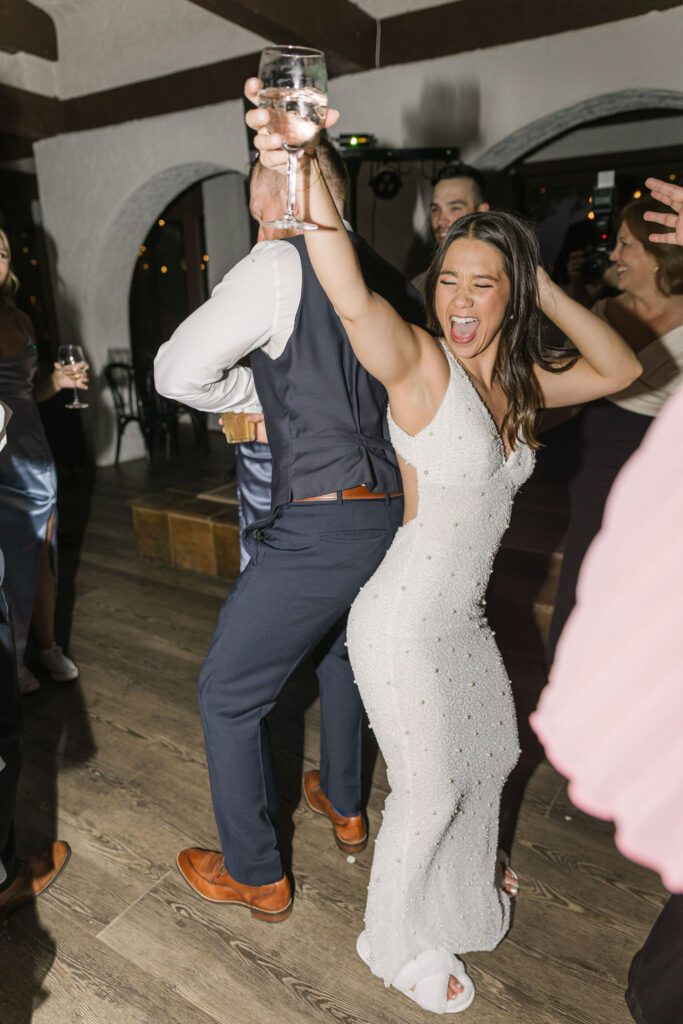 Bride dancing with groom holding drinks at Colorado wedding.