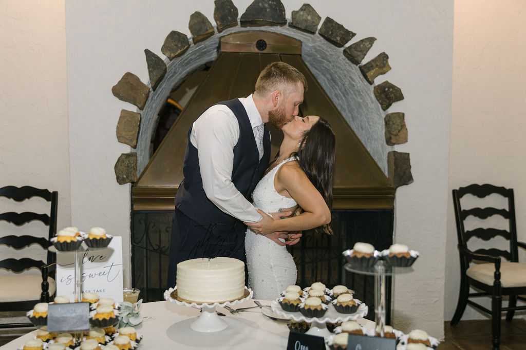 Bride and groom kissing near wedding cake at Villa Parker.