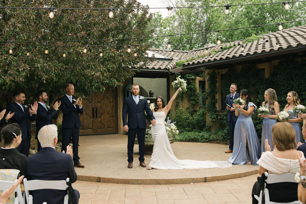 Bride celebrating and raising her bouquet after the ceremony recessional at Villa Parker during their Colorado wedding celebration.