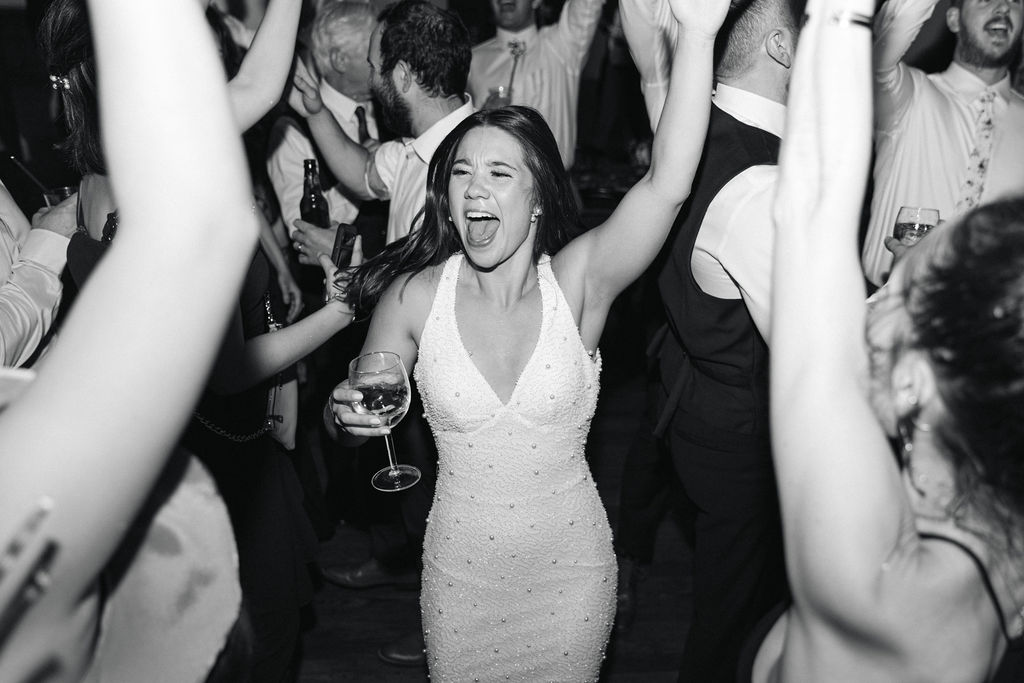 Bride dancing with guests during the lively reception at Villa Parker, captured in candid black-and-white during a Colorado wedding celebration.