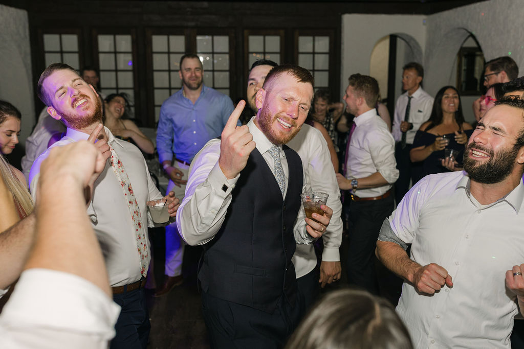 Groom smiling and raising glass while dancing during Colorado wedding.