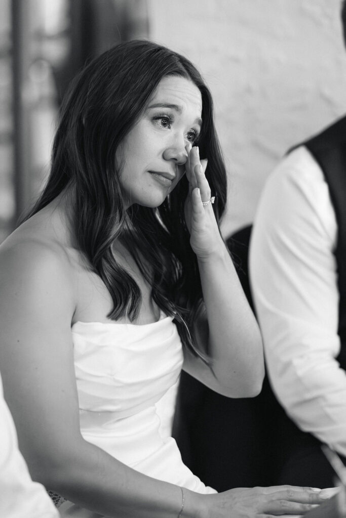 Bride wiping away a happy tear during the maid of honor's speech.