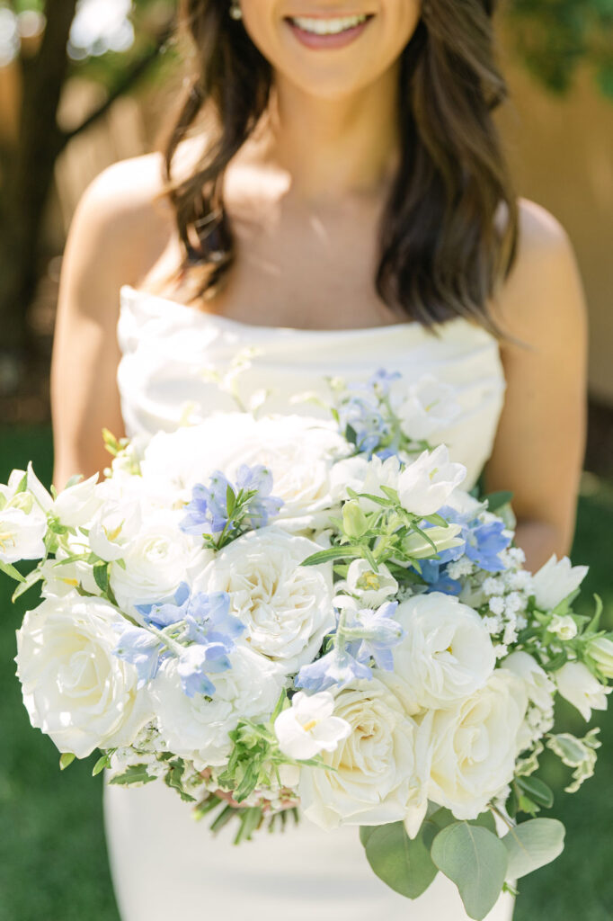 Bride holding white and blue bouquet in the gardens at Villa Parker.