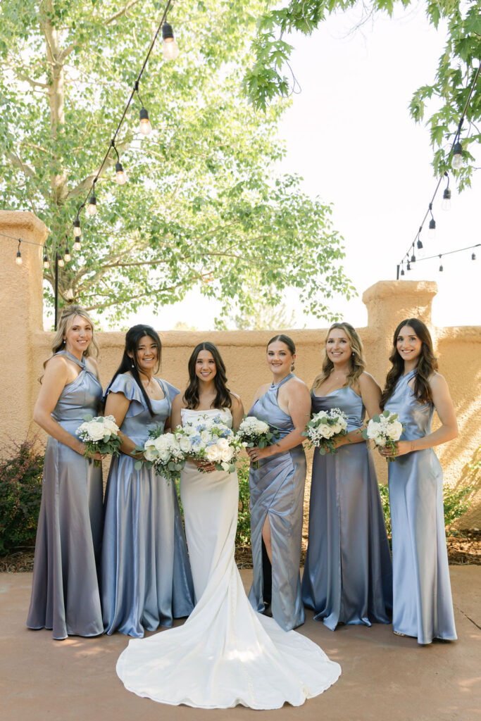 Bride standing with her bridesmaids in slate-blue dresses during a Villa Parker wedding in Colorado, photographed in the European-inspired courtyard.
