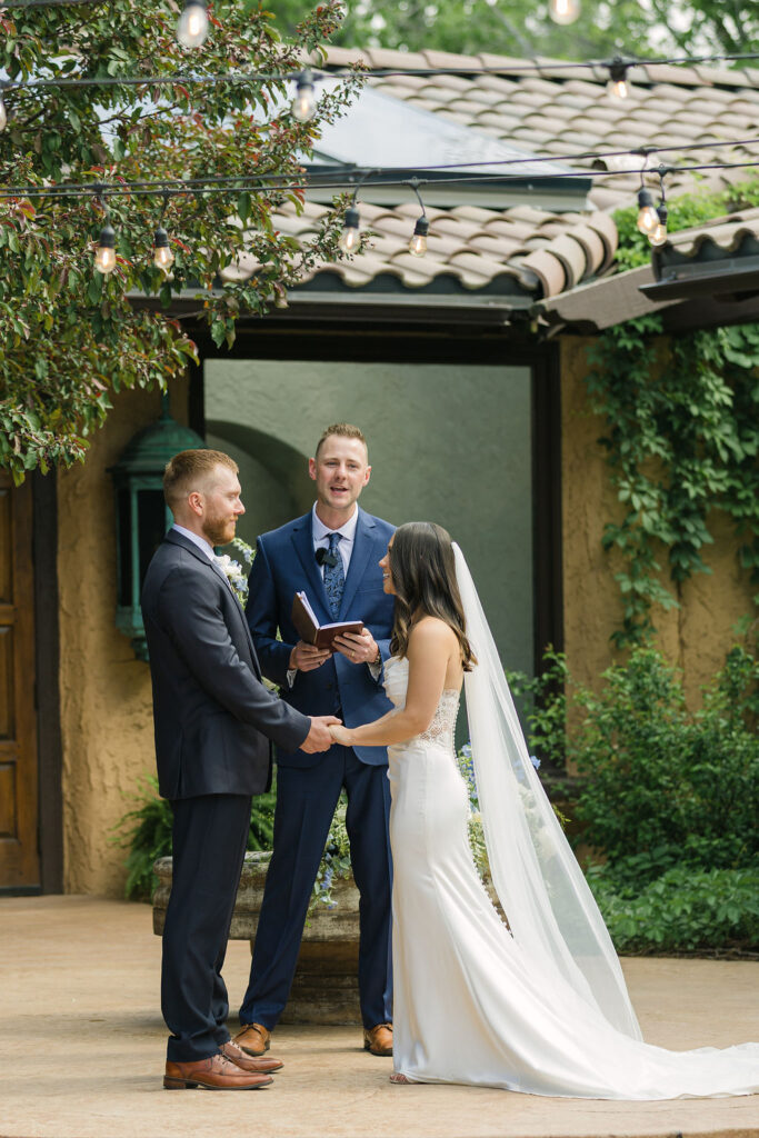 Bride and groom holding hands at the ceremony altar at Villa Parker during their European-inspired Colorado wedding.