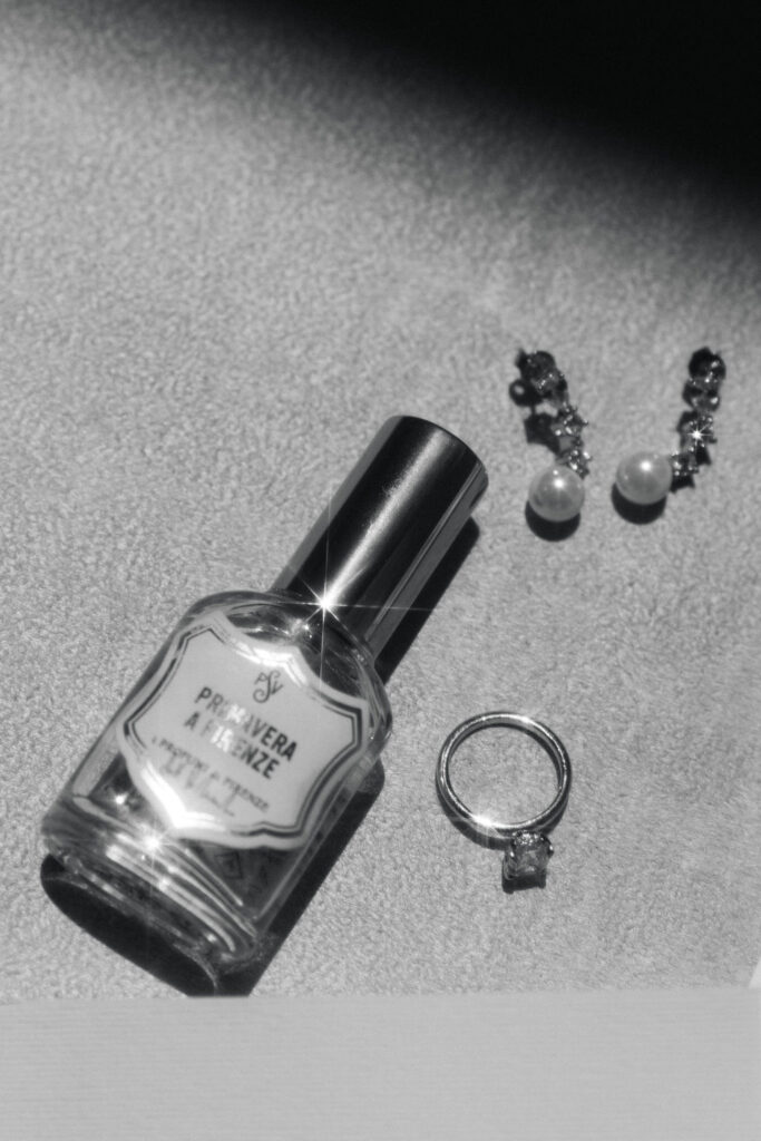 Flatlay of bride’s perfume, earrings, and ring for Colorado wedding details at Villa Parker.