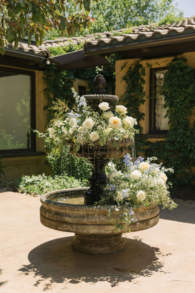 Floral-decorated stone fountain in the courtyard at Villa Parker wedding venue.