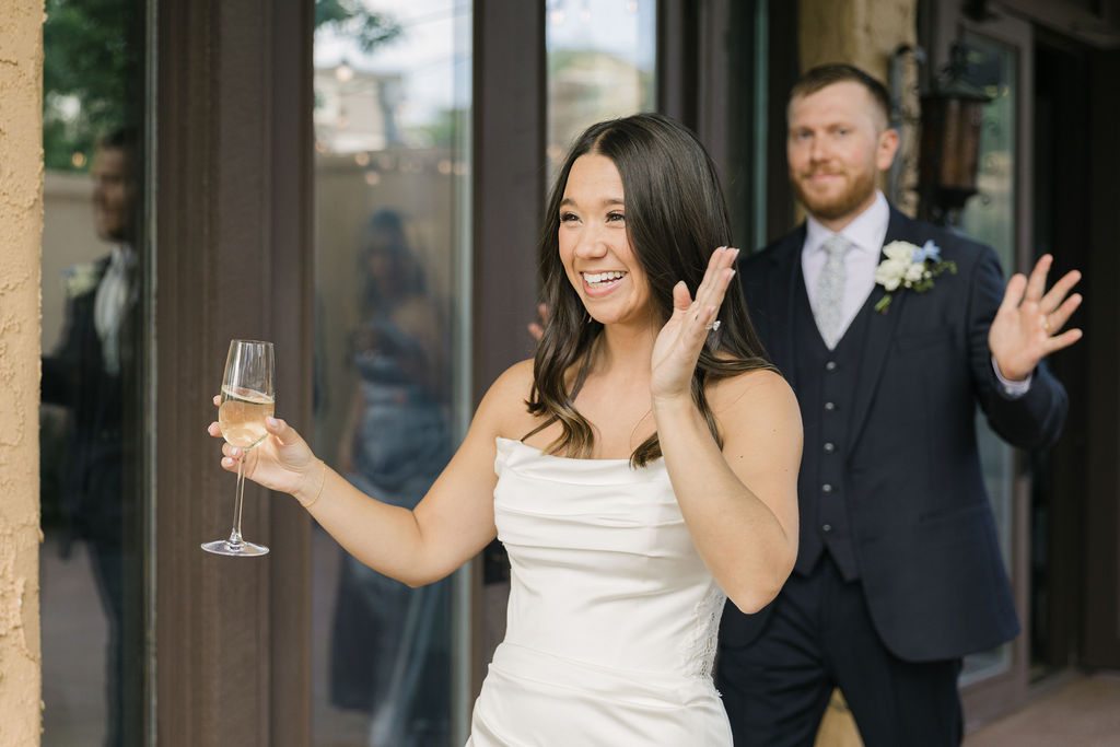 Bride waving while entering cocktail hour at Colorado wedding.