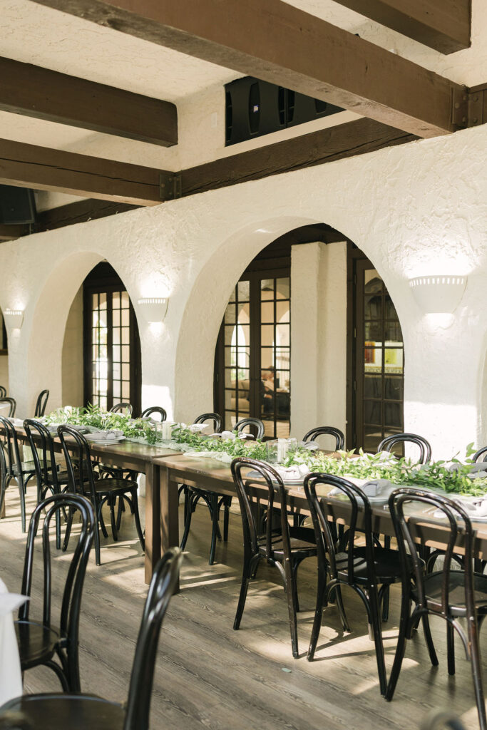 Long reception tables with greenery runners inside Villa Parker wedding venue.
