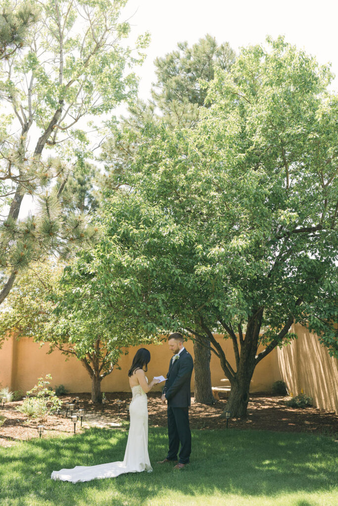 Bride and groom standing together under trees for Colorado wedding portraits.