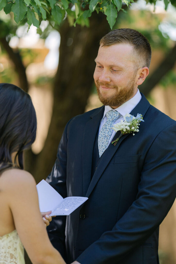 Groom smiling at bride during private vow reading in Villa Parker garden.
