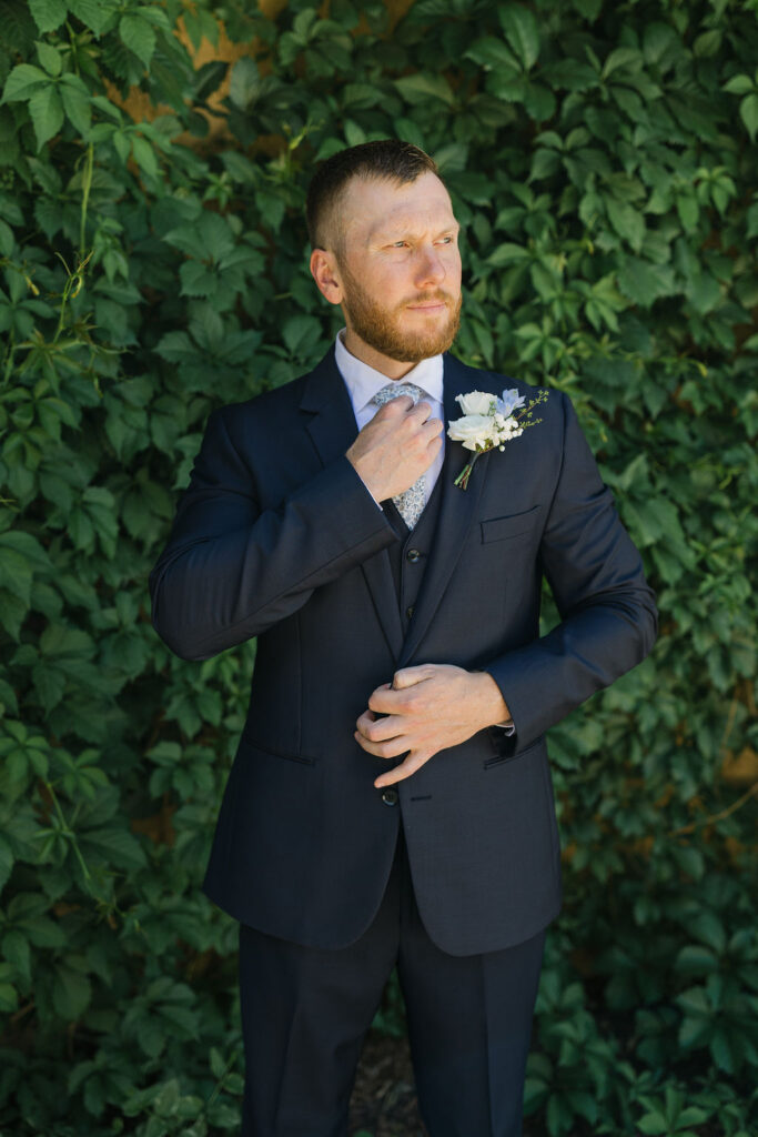 Groom adjusting his boutonniere during outdoor portraits at Villa Parker, captured in timeless Colorado wedding photos.