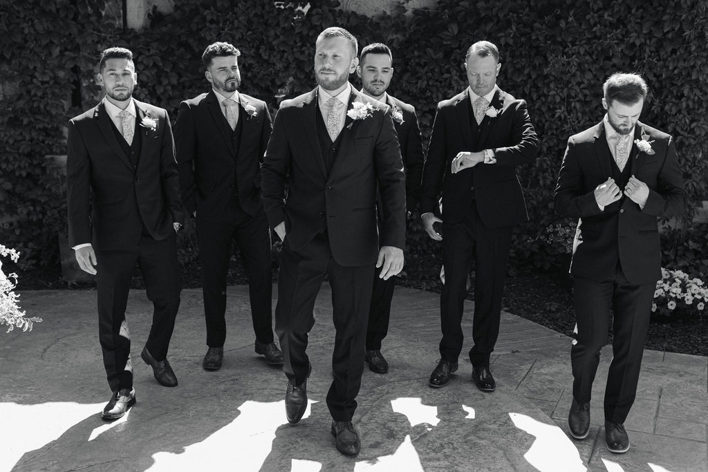 Groom walking confidently with his groomsmen behind him during a Villa Parker wedding, captured in classic black-and-white Colorado wedding portraits.
