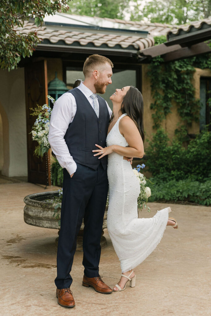 Bride and groom kissing by floral-decorated fountain at Villa Parker.