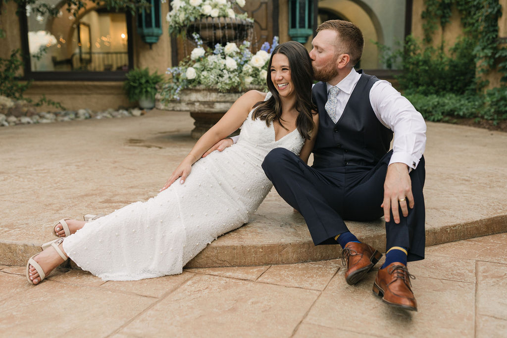 Bride leaning on groom beside courtyard fountain for Villa Parker wedding photos.