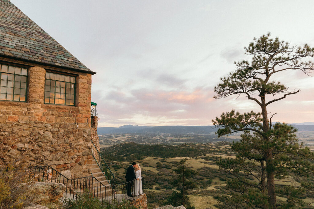 Gorgeous sunset bride and groom kissing on stairs on side of Cherokee Ranch and Castle while overlooking the mountains 