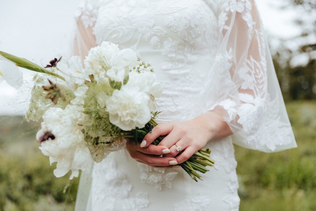 Detail photo of a western bride's white bouquet and rectangular wedding ring during her Jackson Hole elopement