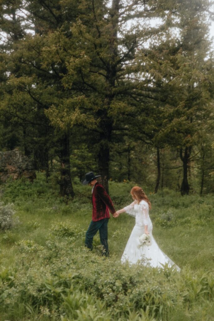 Groom leading his bride through a meadow during their Jackson Hole elopement photos 
