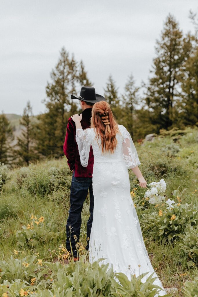 Bride tapping groom on the shoulder during their private first look in a meadow