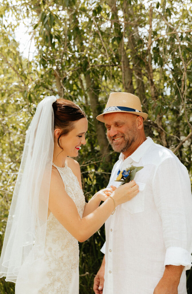 Bride pinning her dad's boutonniere before the wedding ceremony  