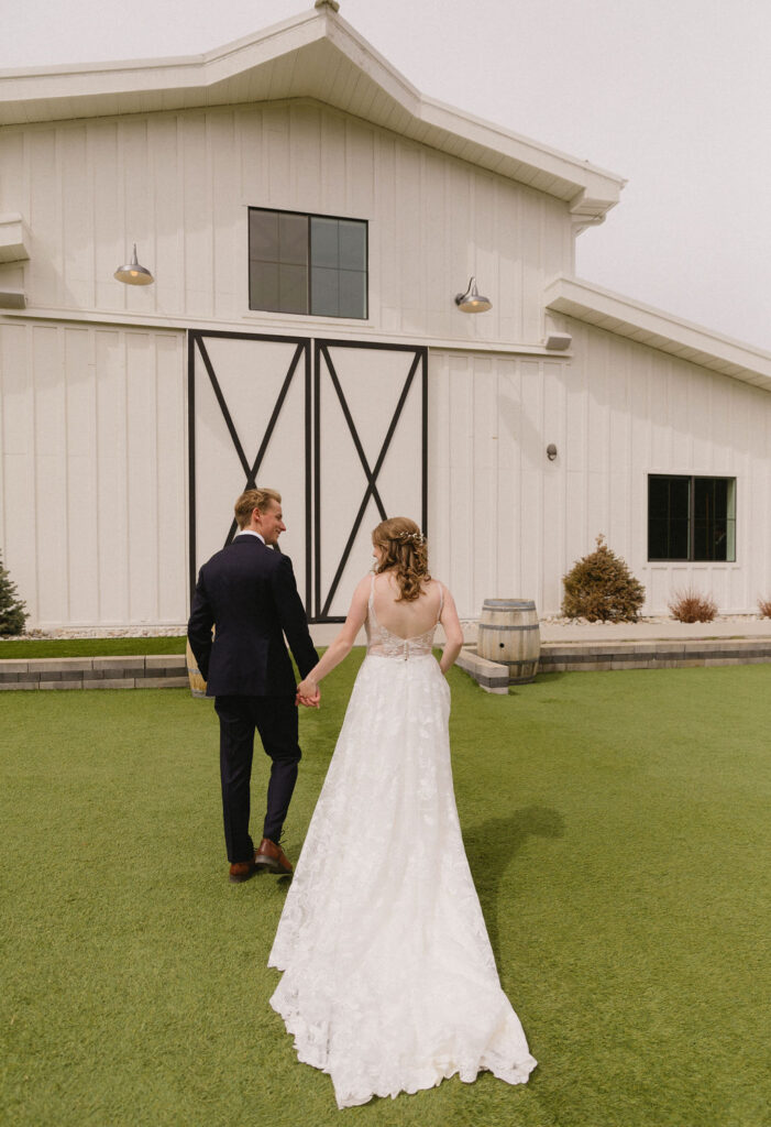 bride and groom in front of woodlands, their elegant white barn wedding venue