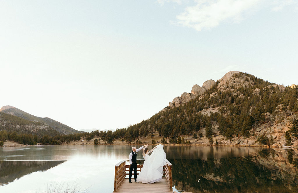 bride and groom dancing on a dock in at a lake in the mountains