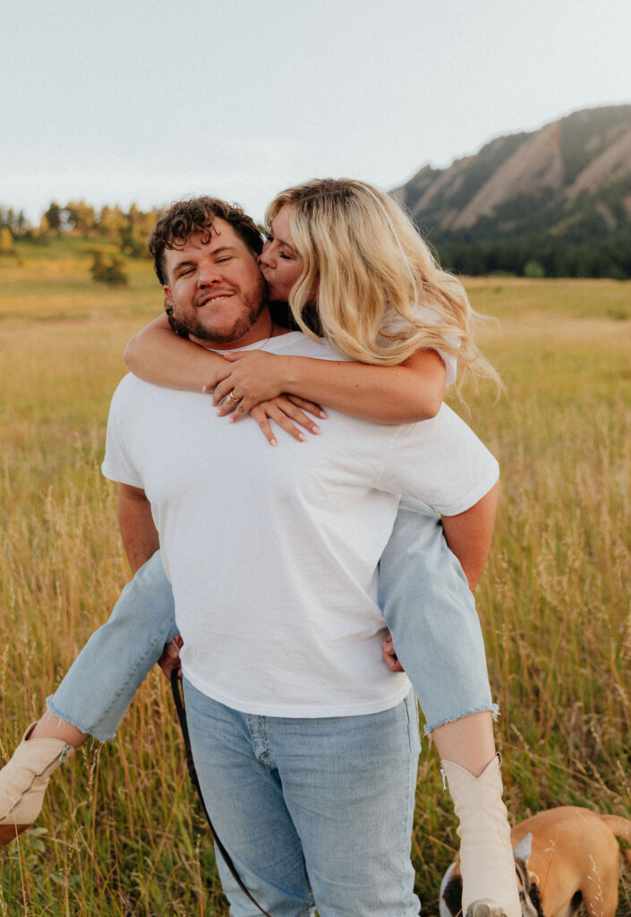 casual golden hour field engagement photos of the couple in white t-shirts and denim at Chautauqua Park