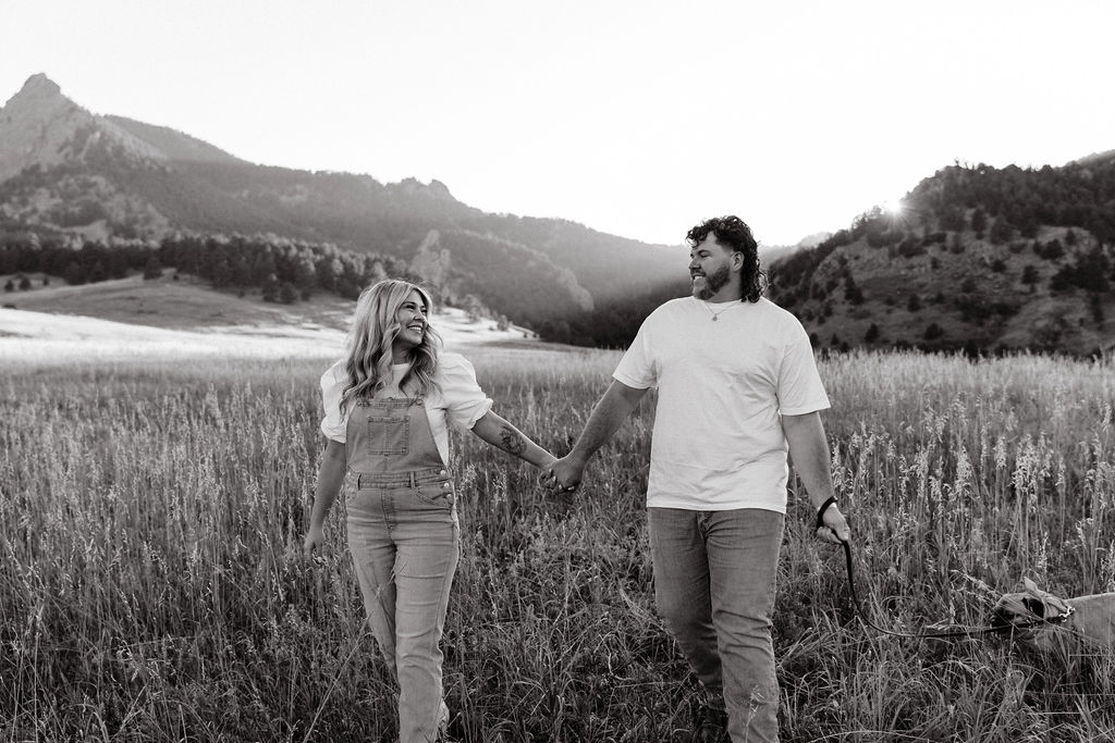 casual golden hour field engagement photos of the couple in white t-shirts and denim at Chautauqua Park