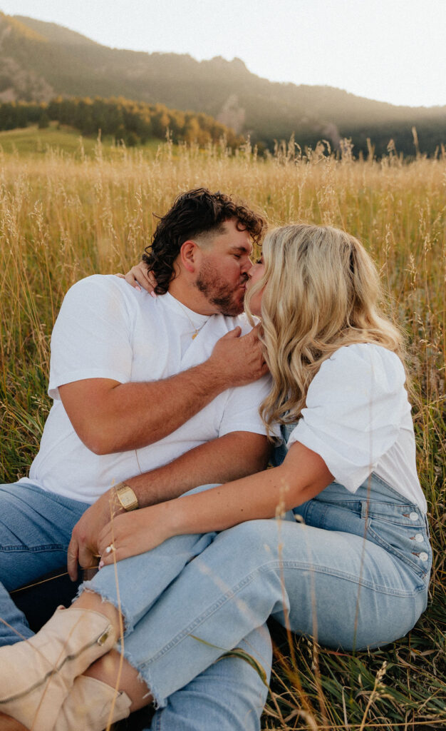 casual golden hour field engagement photos of the couple in white t-shirts and denim at Chautauqua Park