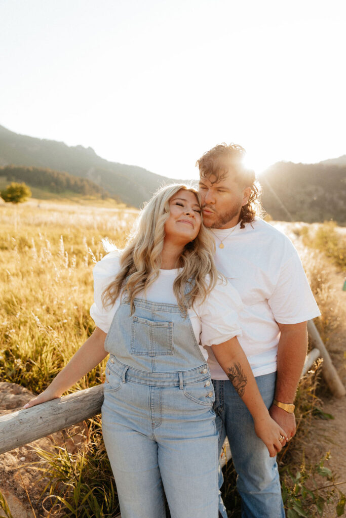 casual golden hour field engagement photos of the couple in white t-shirts and denim at Chautauqua Park