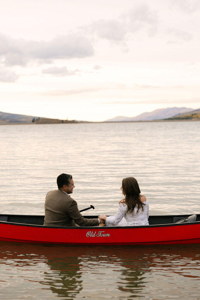 Romantic sunset bride and groom lake portraits at windy point campground in Dillon, Colorado in a red canoe