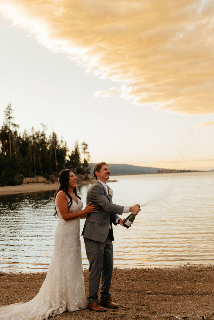 bride and groom popping a bottle of champagne at lake dillon