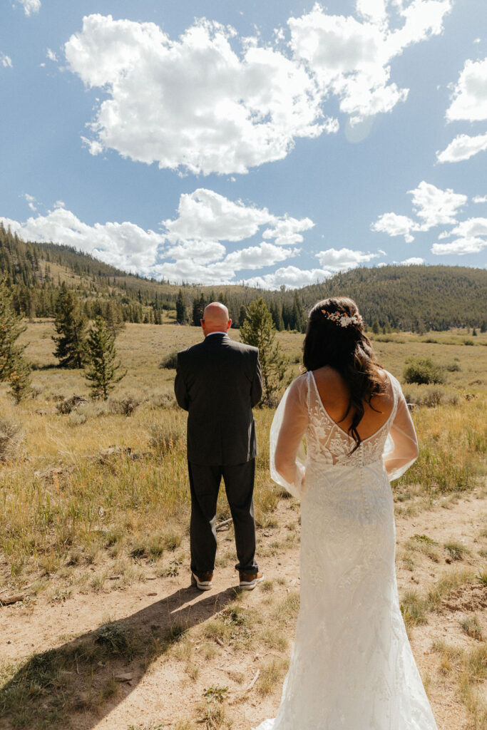 bride and dad first look in a vast open meadow