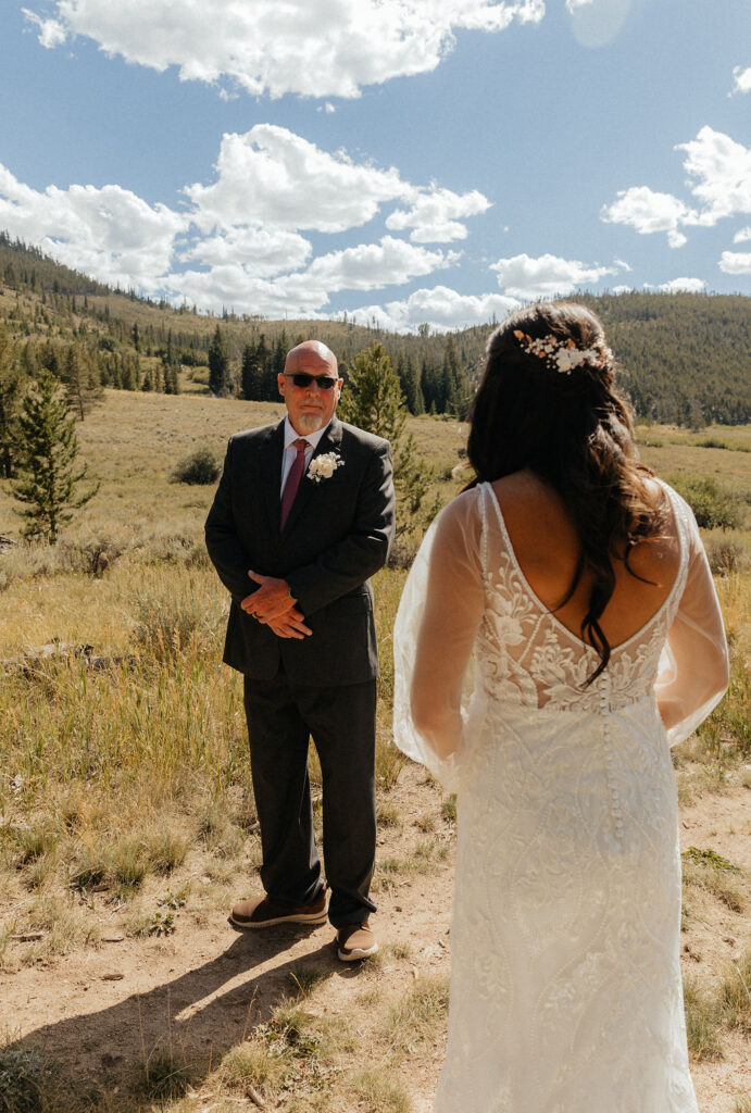 bride and dad first look in a vast open meadow