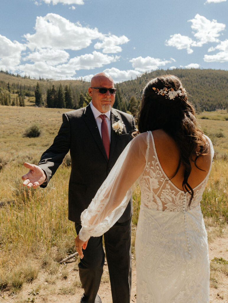 bride and dad first look in a vast open meadow