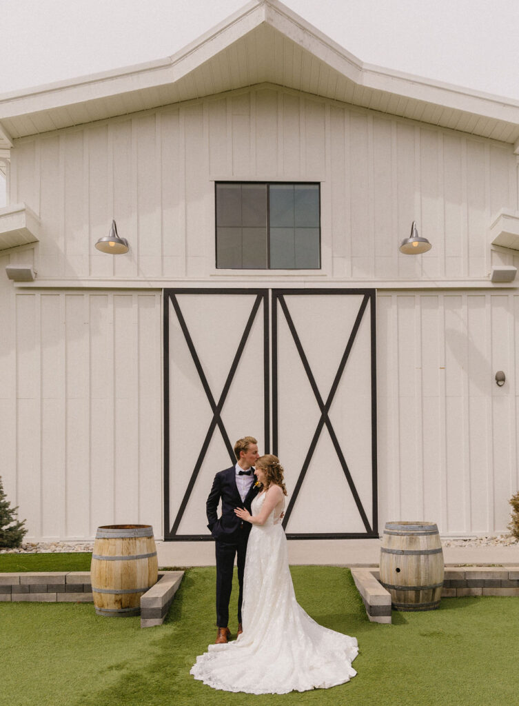 bride and groom in front of woodlands, their elegant white barn wedding venue