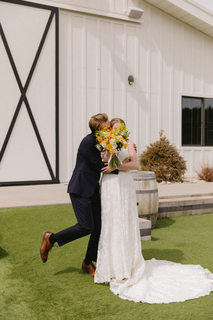 bride and groom in front of woodlands, their elegant white barn wedding venue