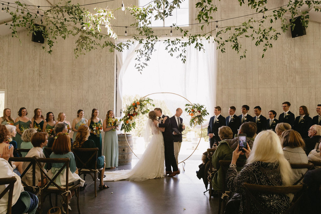 bride and groom first kiss during their wedding ceremony at woodlands