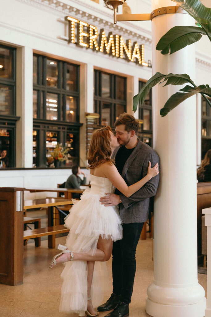 modern chic couple kissing inside the denver union station terminal at their Christmas engagement session