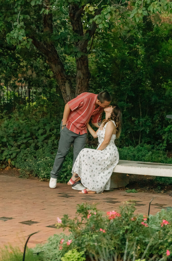 Romantic couple kissing on bench at denver botanic gardens engagement session