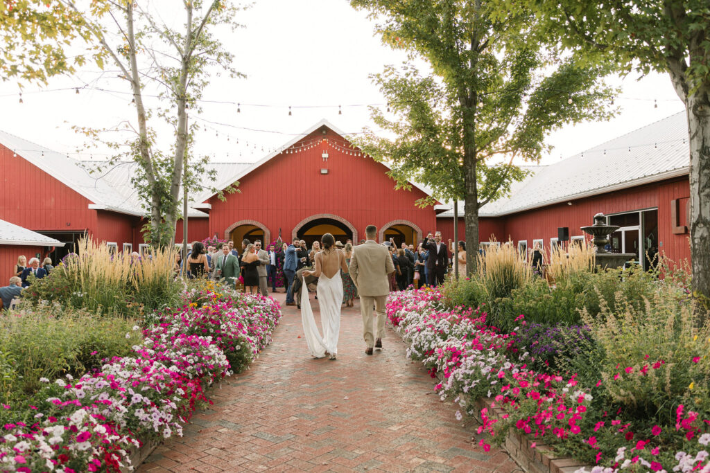 Bride and groom joining cocktail hour outdoors in colorful flowers at the venue at crooked willow farms