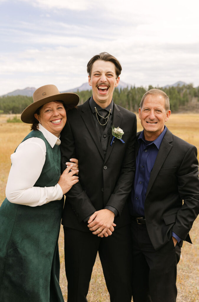 Joyful, candid moment with groom and his parents at his Rocky Mountain National Park mountain wedding.