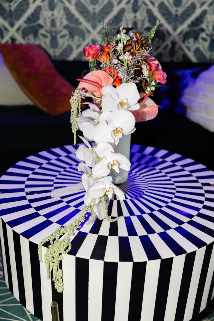 Funky and colorful bridal bouquet captured on a black and white table under neon blue lights at an elopement in Boulder.