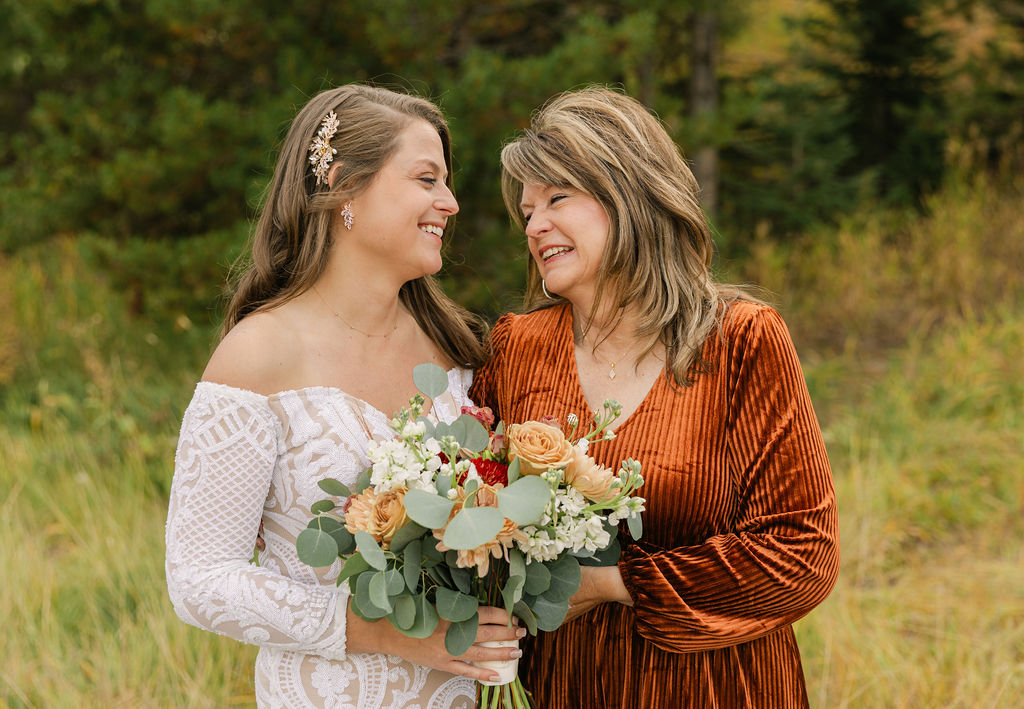 Bride sharing a candid moment with her mom laughing as they take their formal wedding day portraits at a fall wedding at Lake Dillon.