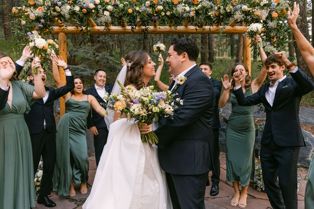 happy bride and groom surrounded by their excited cheerful wedding party