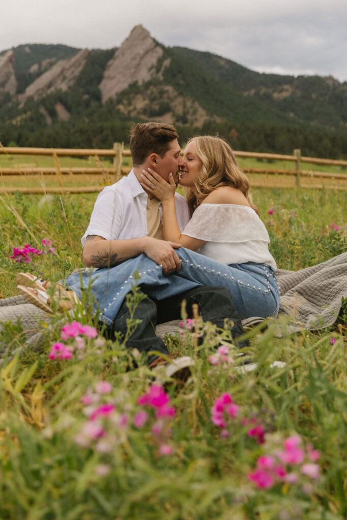 Close-up of engaged couple kissing among pink wildflowers at Chautauqua Park, premiere Colorado engagement photo location