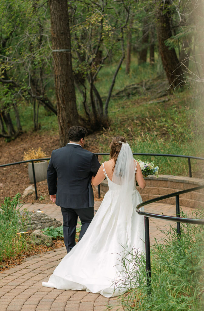 bride and groom walking together hand in hand through the forest during their wedding at the Pines by Wedgewood Weddings