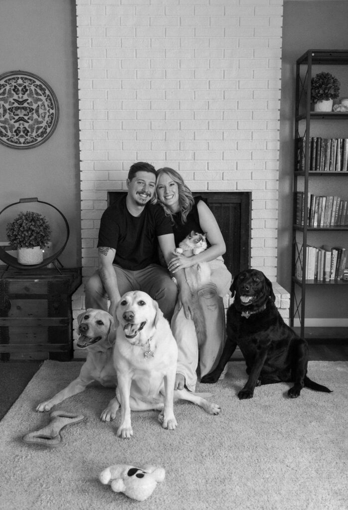 Sweet couple cuddling with their three dogs and cat in their cozy living room couch during their in-home engagement session in Colorado.